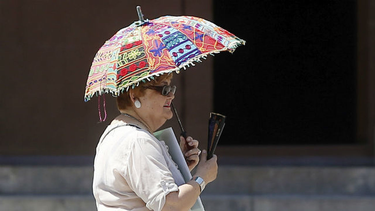 Una señora se protege del sol con una sombrilla