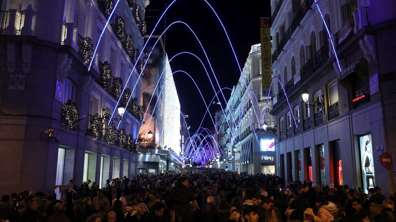 Personas paseando por  la calle Preciados de Madrid, durante el tradicional encendido de luces de Navidad. (EFE)