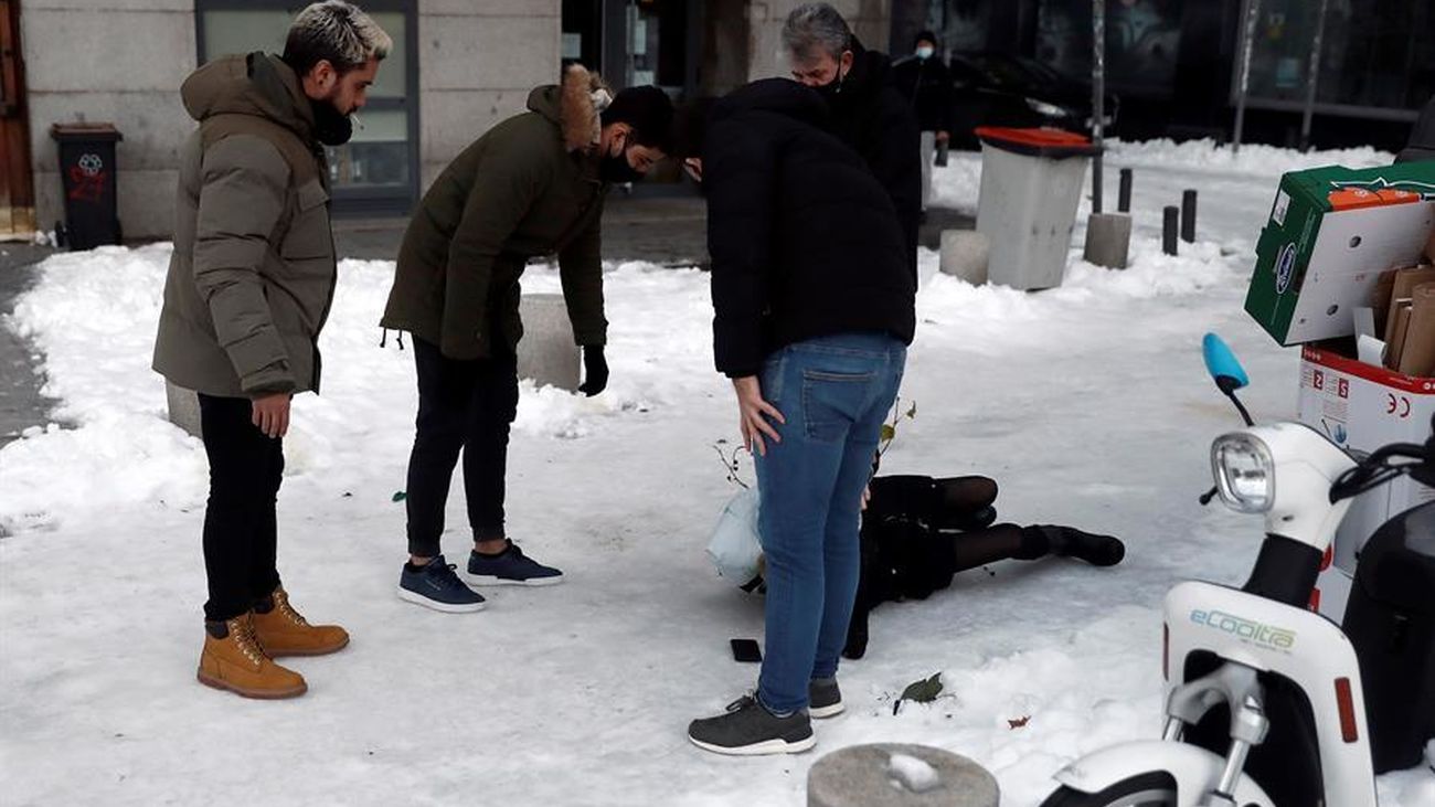 Madrileños atienden a una persona en el suelo tras caer por el hielo
