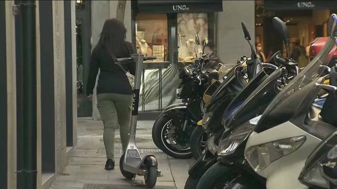 Patinetes y motos aparcados en la acera en Madrid