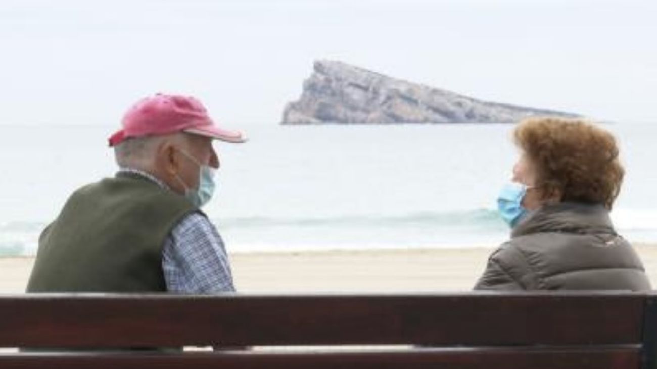 Dos personas sentadas frente a la playa alicantina de Benidorm