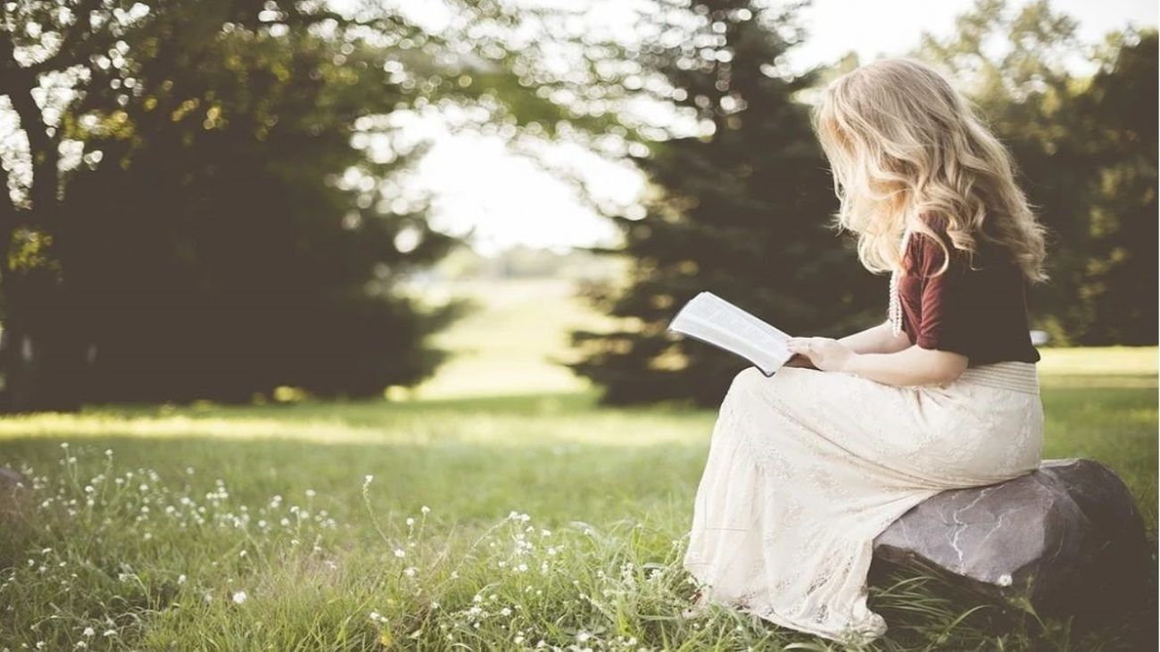 Una joven lee en mitad del campo