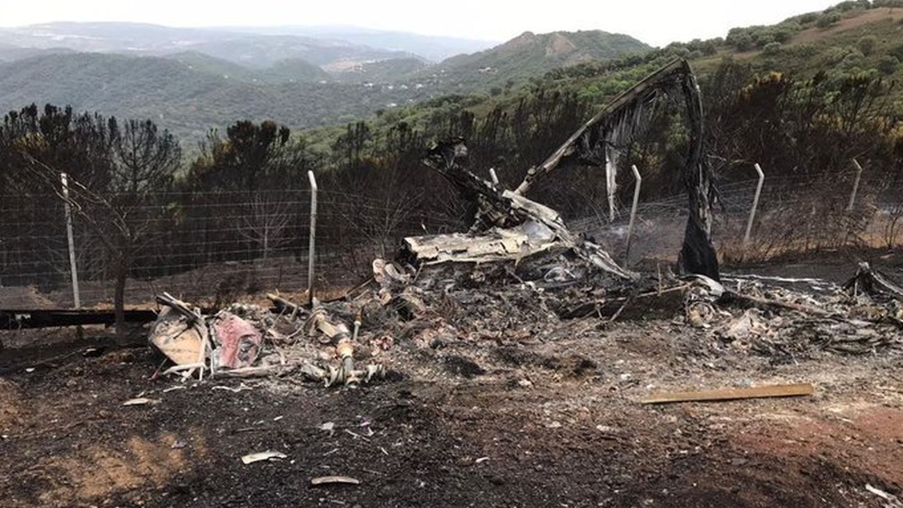 El helicóptero accidentado este lunes, calcinado por las llamas del incendio de Sierra Bermeja