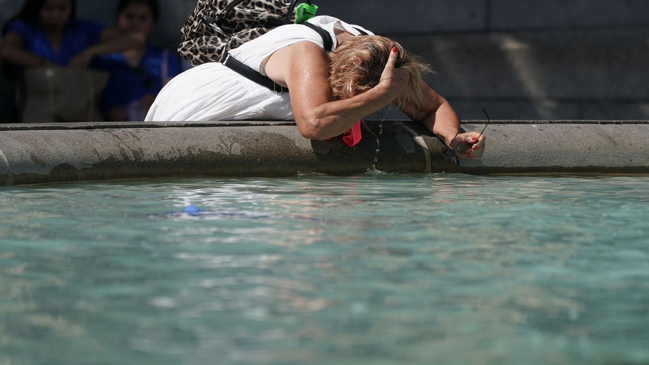 Una mujer se moja la cabeza en una fuente