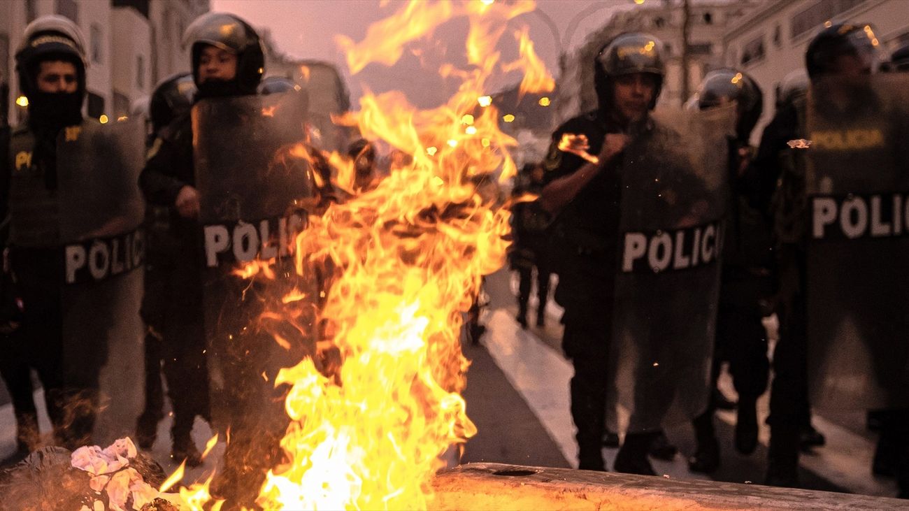 Oficiales de policía detrás de barricadas en llamas encendidas por simpatizantes del derrocado presidente Castillo de Perú