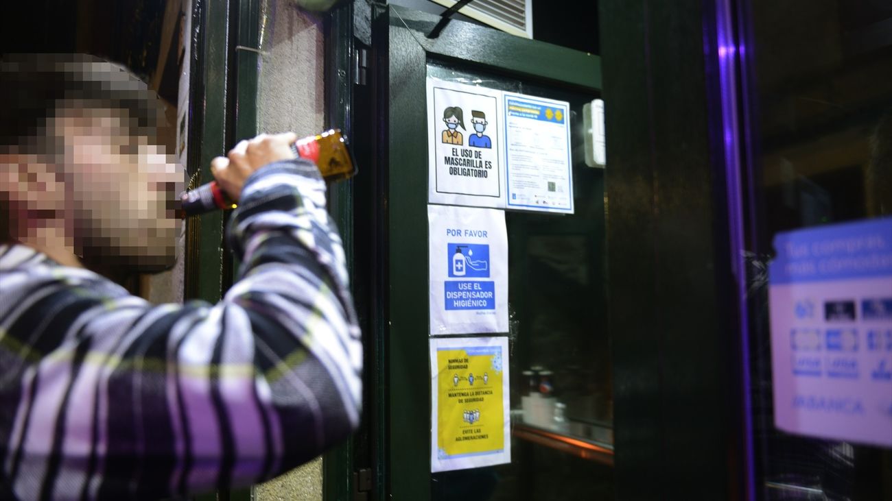 Un joven bebe una cerveza frente a la puerta de un local de ocio nocturno