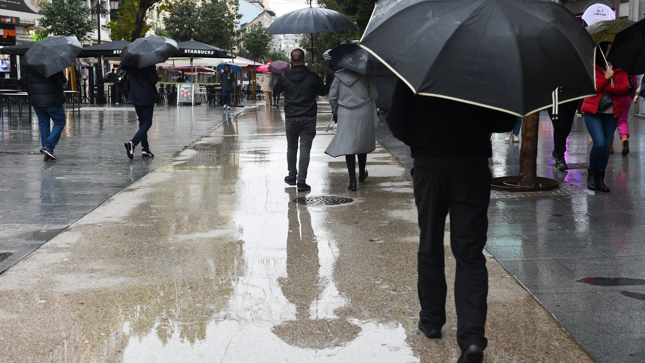 Personas caminan por la calle bajo la lluvia en Madrid