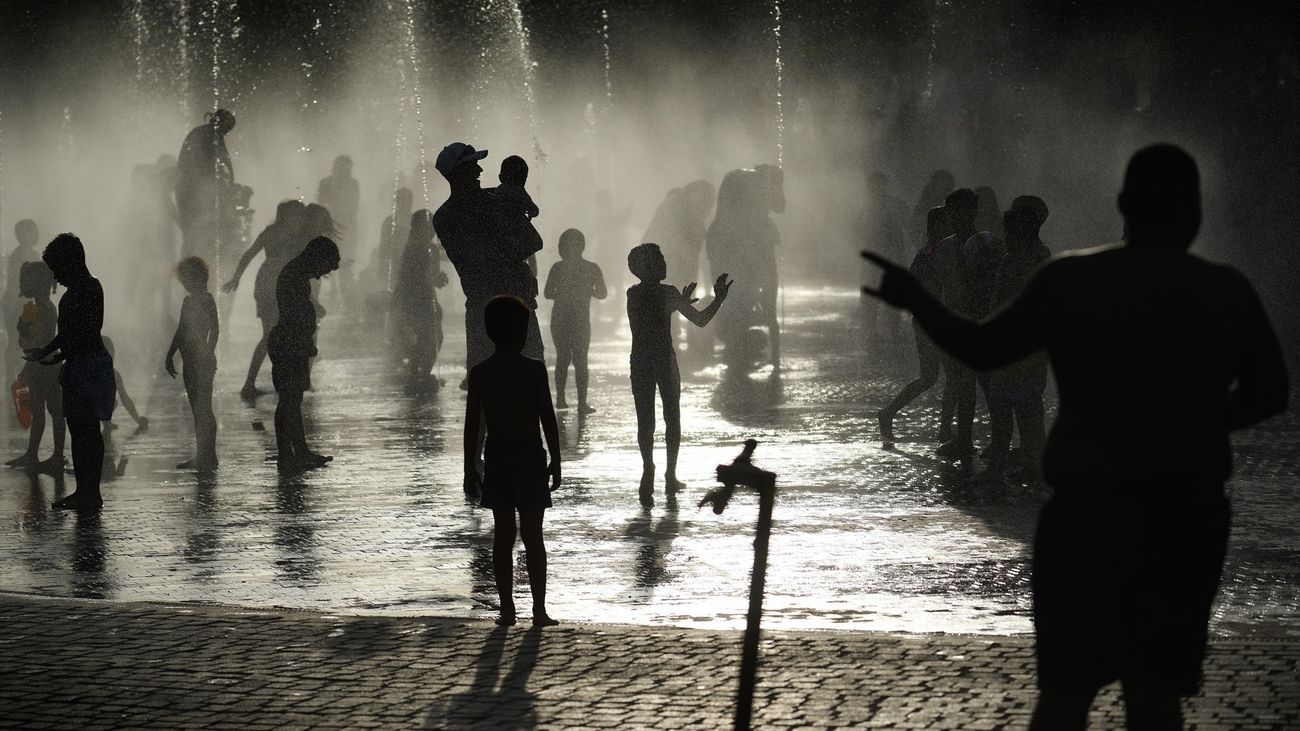 Varias personas, entre ellas niños, se refrescan en los chorros de Madrid Río
