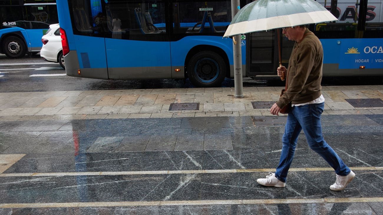 Un hombre con paraguas camina bajo la lluvia por el centro de Madrid