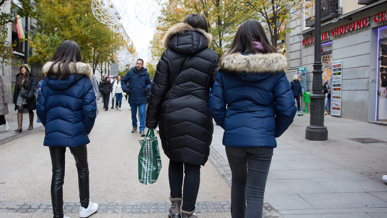 Varias personas caminan por la calle bien abrigadas contra el frío