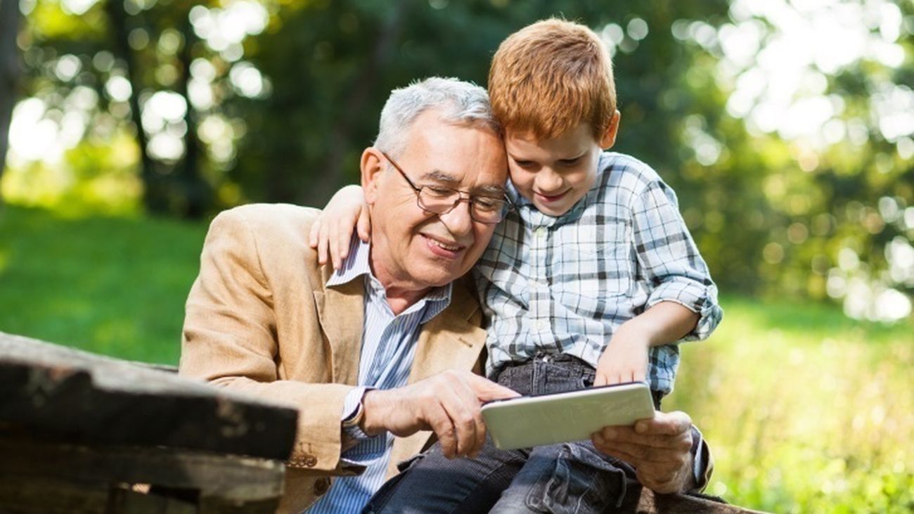 Un abuelo y su nieto comparten un dispositivo electrónico