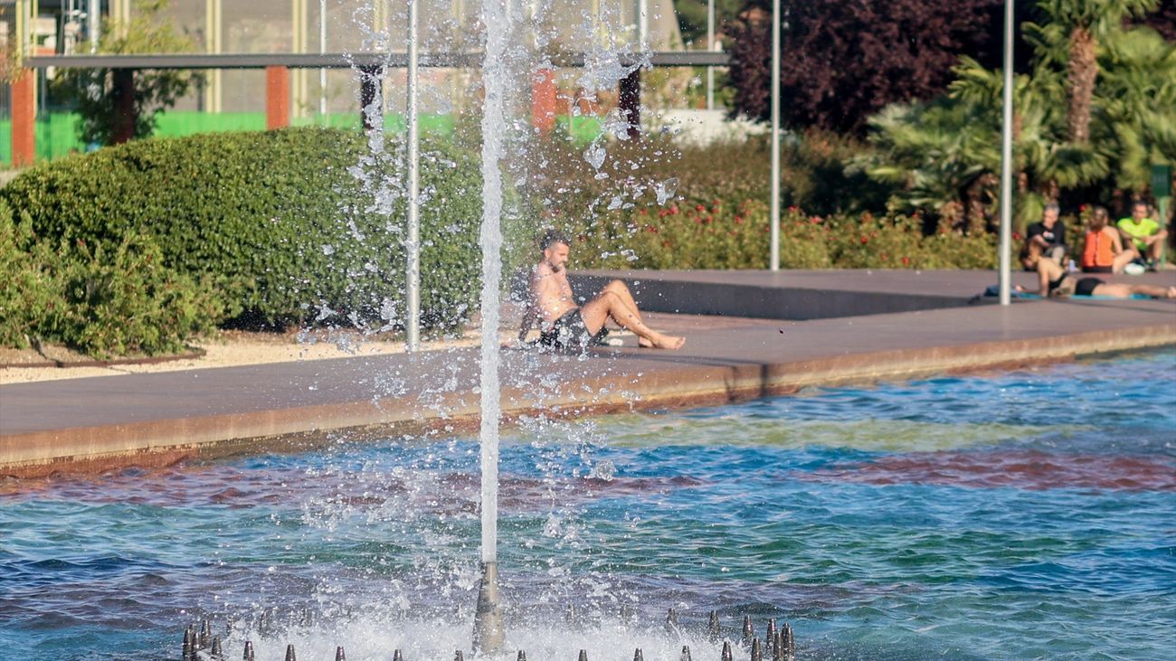 Varias personas se refrescan durante la primera ola de calor, en el parque del Canal de Isabel II