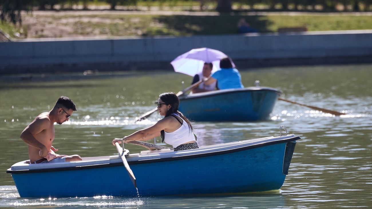 Dos personas en una barca del largo del parque de El Retiro durante la ola de calor