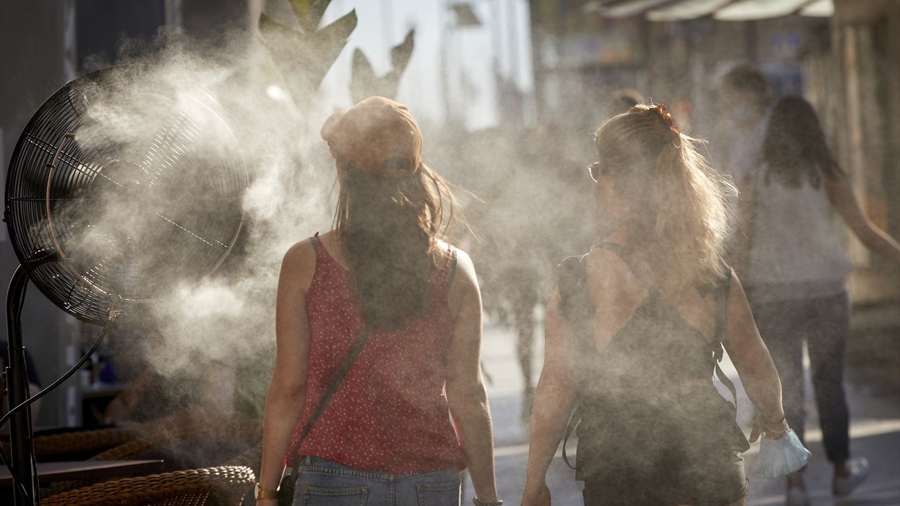 Varias personas caminan al lado de un difusor de vapor de agua de un restaurante de la calle Alcalá