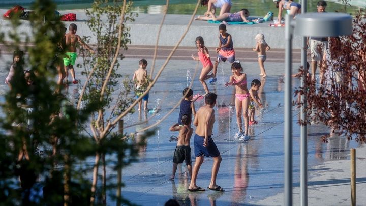 Varias personas se refrescan en el parque del Canal de Isabel II