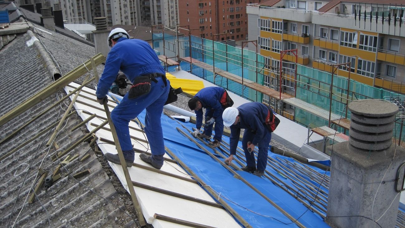 Varios trabajadores en una obra sobre un tejado.