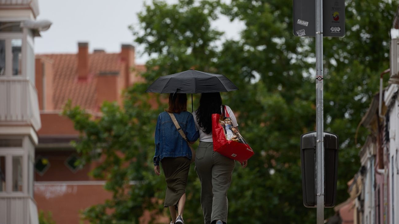 Dos mujeres se protegen de la lluvia en Madrid con un paraguas