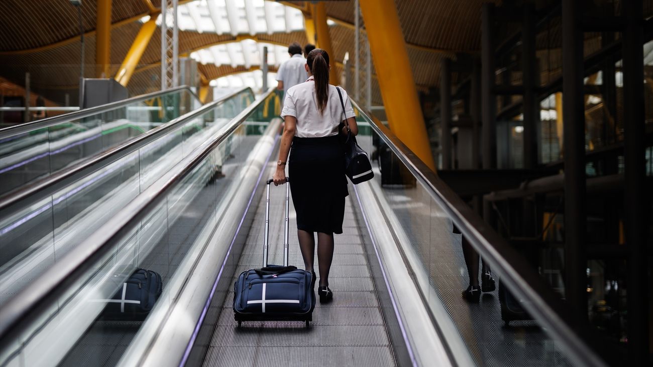 Una azafata en las escaleras mecánicas de la Terminal 4 del aeropuerto de Barajas