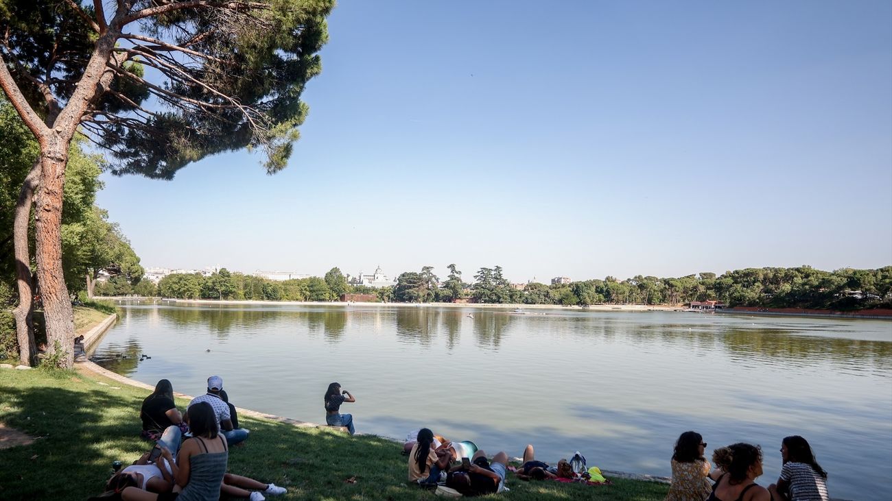 Varias personas sentadas en la orilla del lago de la Casa de Campo