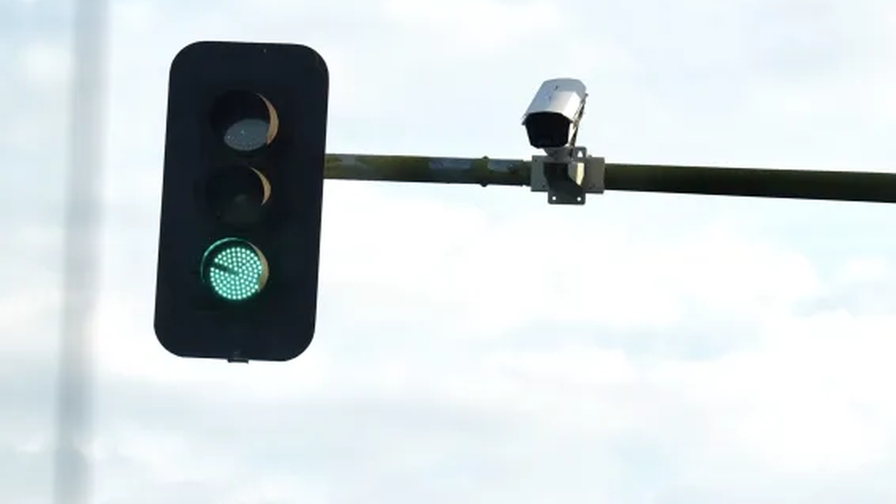 Un semáforo en fase de verde con una cámara de control de tráfico