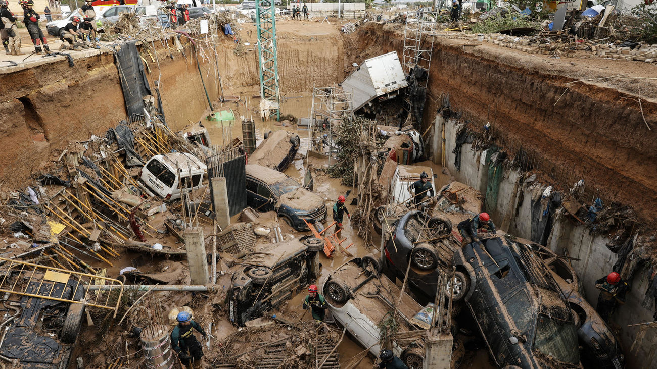 Expertos de la Guardia Civil buscan cuerpos sin vida entre los vehículos atrapados entre los cimientos de un edificio en construcción, este sábado, en Paiporta