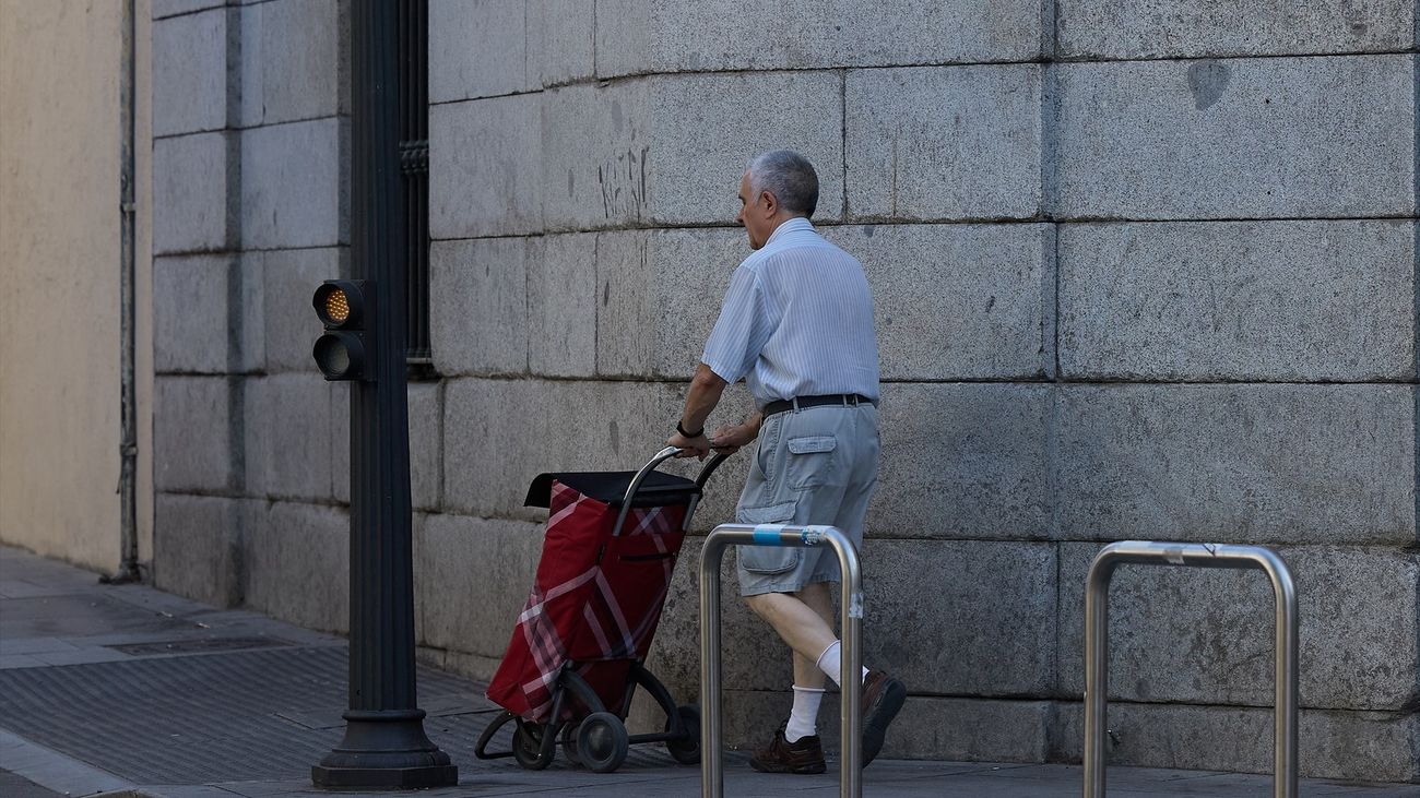 Una persona mayor camina con un carrito por una calle de Madrid