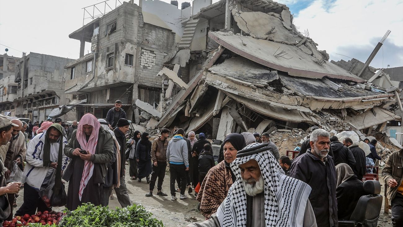 Palestinos hacen compras en un mercado rodeado de edificios destruidos, en Khan Younis,